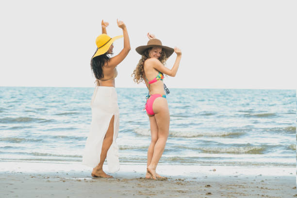 Happy women dance on sand beach in summer.