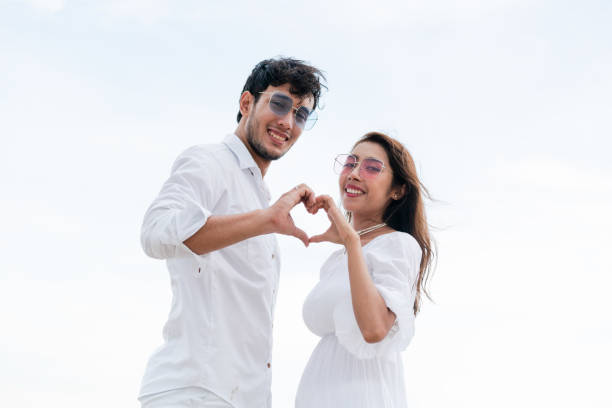 Young couple shows heart shape hand gesture.