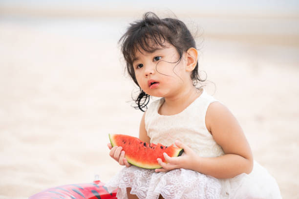 Adorable kid eating watermelon on the beach.