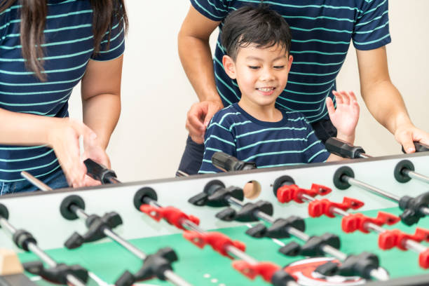 Happy kid playing foosball table with family.