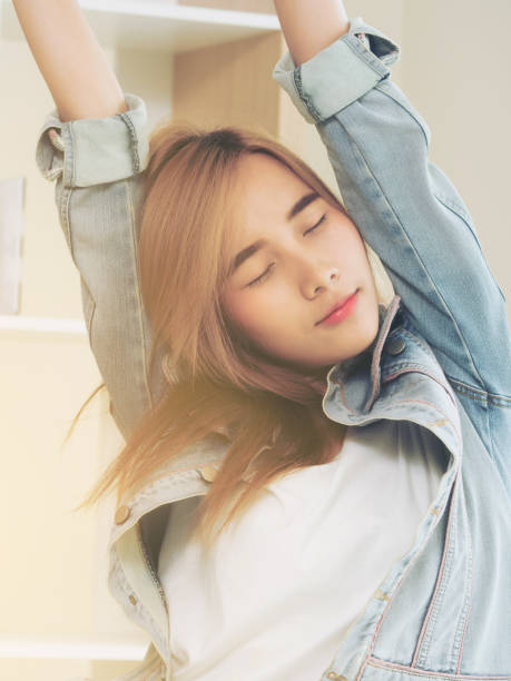 Relaxed woman stretches arms in office.