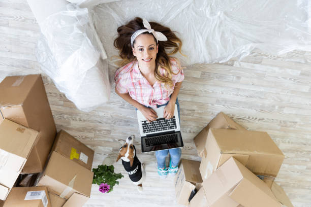 istock Young woman with dog lying on sofa using laptop 1004688754