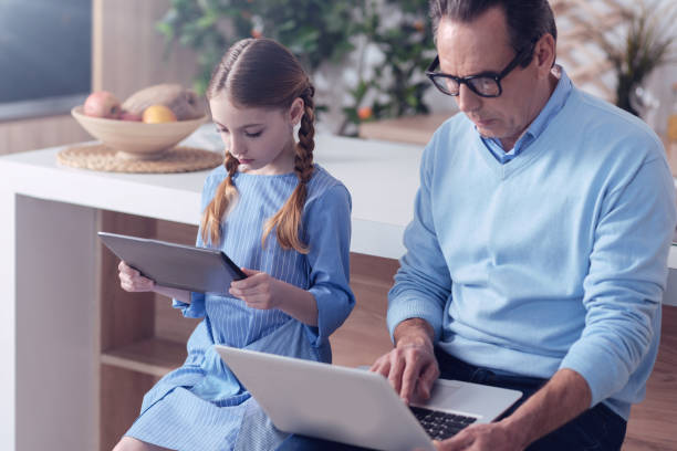 istock Nice serious father and daughter sitting together 1004690954