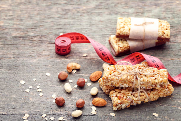 istock Granola bars with different nuts and measuring tape on wooden table 1004709382