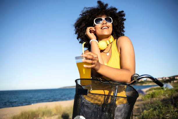 istock Cheerful african woman drinking yellow cocktail on beach 1004712152