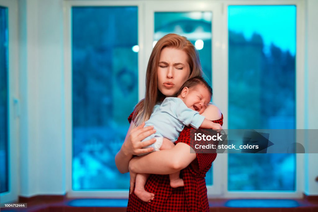 baby girl crying baby girl in her mothers arms crying, mother frowning and suffering together. Postpartum Depression Stock Photo