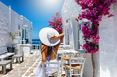 Woman enjoys the classic setting of white houses and colorful flowers on the cyclades islands of Greece