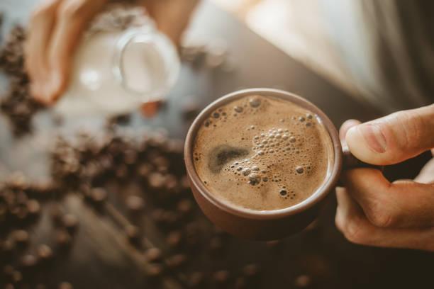 istock Man pouring milk in steamed coffee 1004737922