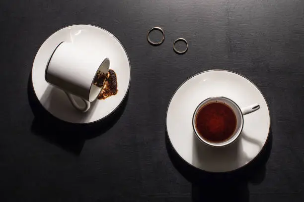 Two engagement rings on the table and drunk coffee and empty mugs are the concept of divorce and separation of lovers.