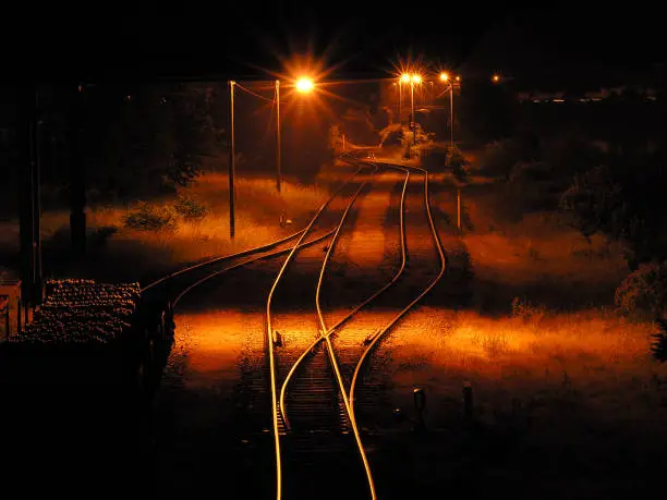Empty freight yard with parked wagon and orange street lights at night