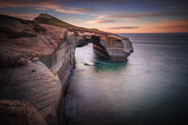 Limestone Archway to Harmony A sunrise long exposure at Tunnel Beach, Dunedin - New Zealand dunedin new zealand stock pictures, royalty-free photos & images