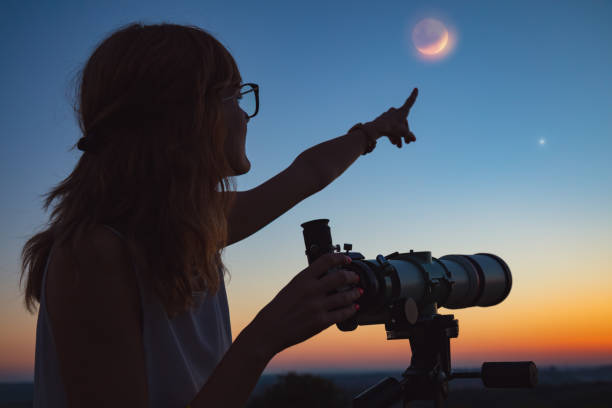 istock Girl looking at lunar eclipse through a telescope. My astronomy work. 1004772712