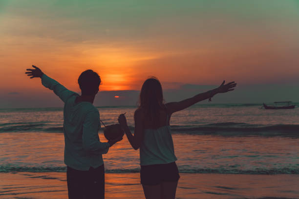 Couple drinking cocnut juice while watching the sunset over the ocean in Bali, Indonesia.