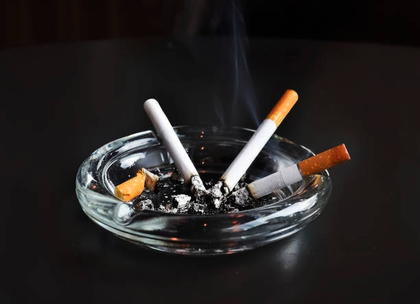 istock lit cigarettes in the ashtray - unhealthy habbits icon - black background 1004775608