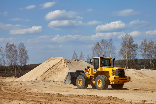 Front end loader scoops up a sand near an aerated concrete plant