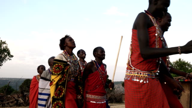 a group of maasai women and men dance in pairs