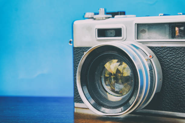 istock vintage camera on wooden table over blue background 1004789238