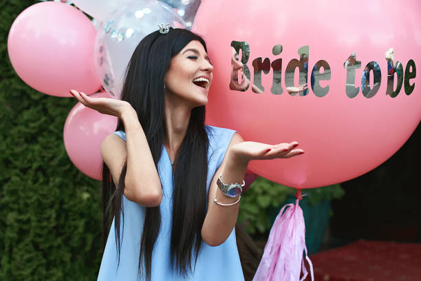 Happy young beautiful brunette bride to be with dark hair and silver crown smiling and spreading out her hands in joy on bachelorette pink party balloon background Happy young beautiful brunette bride to be with dark hair and silver crown smiling and spreading out her hands in joy on bachelorette pink party balloon background bachelorette party stock pictures, royalty-free photos & images