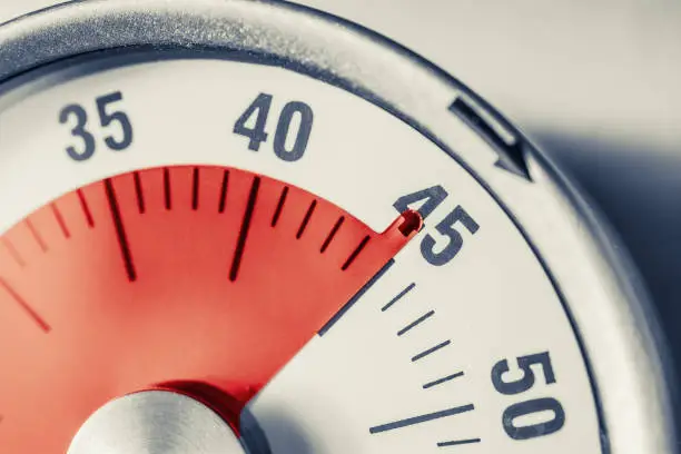 Photo of 45 Minutes - Analog Kitchen Timer With Red Mark Placed On A Fridge In Monochrome Colors