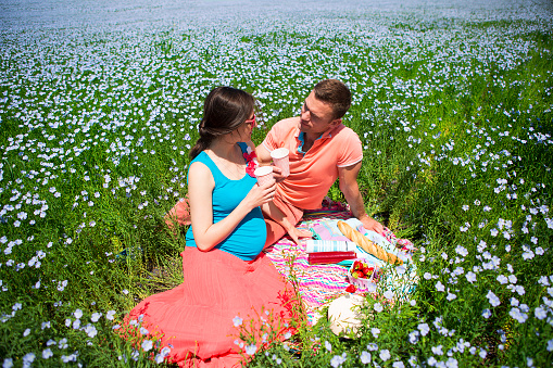 Portrait of a young happy beautiful pregnant couple in linen field