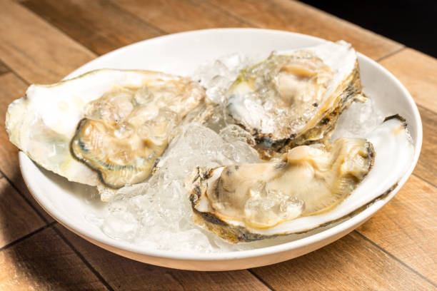 istock Close up of Fresh opened oyster offered as top view on crushed ice. 1004807254