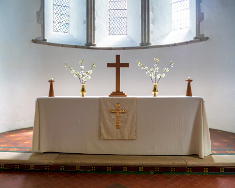 A simply furnished altar on a clean white altar cloth inside the parish church of St Martin of Tours parish church in the pretty village of Eynsford in Kent, Southeast England.