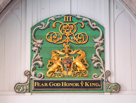 The Royal Arms of King George III inside the parish church of St Martin of Tours parish church in the pretty village of Eynsford in Kent, Southeast England. The Arms bear the motto 'Fear God Honor Ye King’. Royal Arms were hung in churches from the reign of King Henry VIII to remind the congregation that the Pope was no longer the head of the church - that it was now the Monarch.