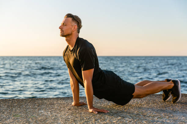 istock handsome adult sportsman doing backbend while stretching on seashore 1004821144