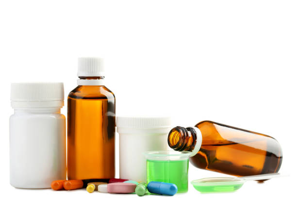 istock Bottles, measuring plastic cup with medical syrup and capsules on white background 1004830540