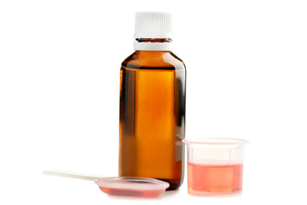istock Bottle, measuring plastic cup and spoon with medical syrup on white background 1004830658