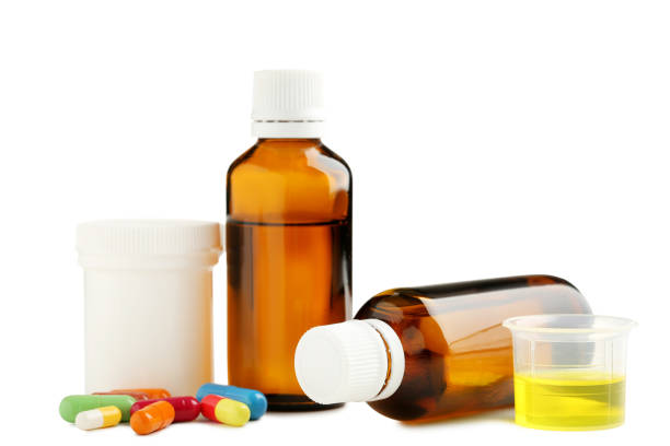 istock Bottles, measuring plastic cup with medical syrup and capsules on white background 1004830806