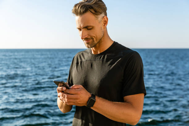 istock handsome adult man with smartphone on seashore 1004830940