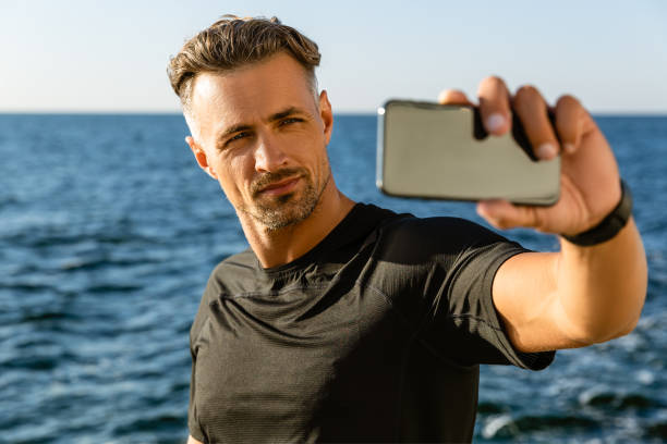istock handsome adult man taking selfie with smartphone on seashore 1004830968