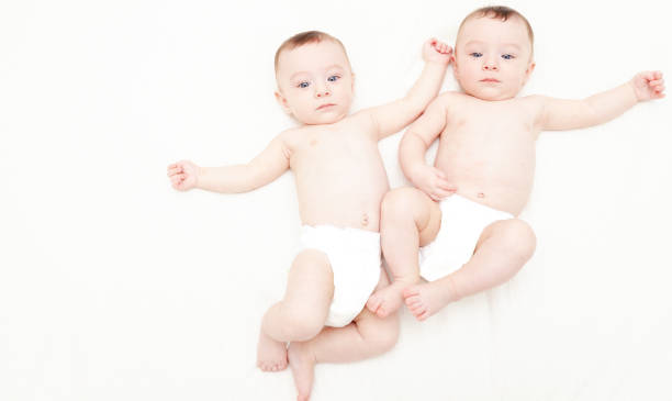 istock Identical twin baby boys in diapers looking at camera on white 1004835890