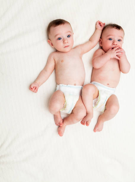 istock Identical twin baby boys in diapers looking at camera on white 1004835974