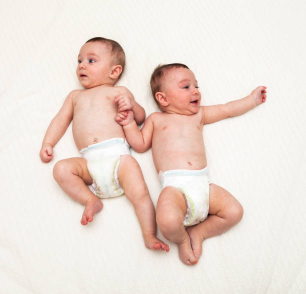 istock Identical twin baby boys in diapers looking away on white 1004835996