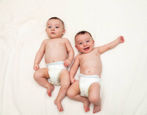 istock Identical twin baby boys in diapers looking at camera on white 1004836014