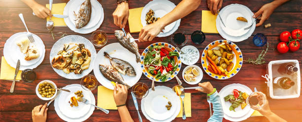 grande cena in famiglia in corso. immagine verticale vista dall'alto sul tavolo con cibo e mani - meeting food nature foods and drinks foto e immagini stock