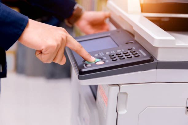istock Close-up business man Hand press button on panel of printer, printer scanner laser office copy machine supplies start concept. 1004836284