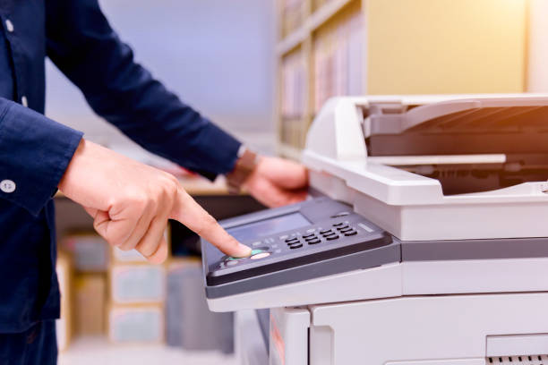 istock Close-up business man Hand press button on panel of printer, printer scanner laser office copy machine supplies start concept. 1004836332