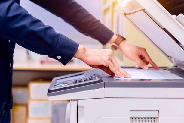 istock Close-up business man Hand press button on panel of printer, printer scanner laser office copy machine supplies start concept. 1004836342
