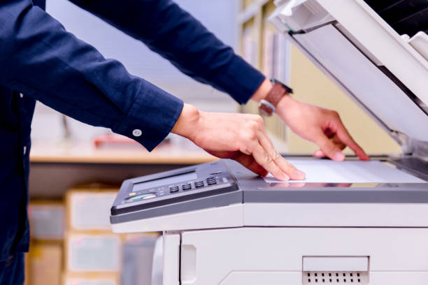 istock Close-up business man Hand press button on panel of printer, printer scanner laser office copy machine supplies start concept. 1004836368