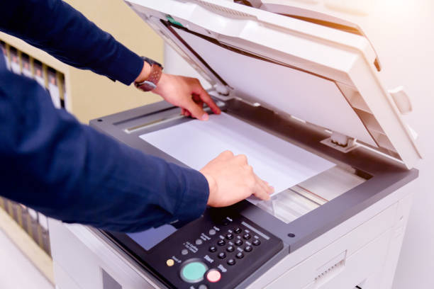 istock Close-up business man Hand press button on panel of printer, printer scanner laser office copy machine supplies start concept. 1004836390