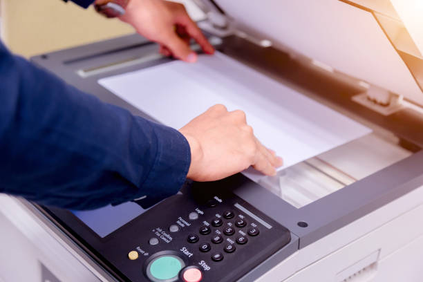istock Close-up business man Hand press button on panel of printer, printer scanner laser office copy machine supplies start concept. 1004836416