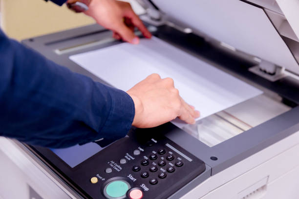 istock Close-up business man Hand press button on panel of printer, printer scanner laser office copy machine supplies start concept. 1004836420