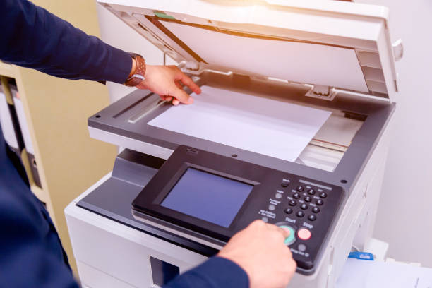 istock Close-up business man Hand press button on panel of printer, printer scanner laser office copy machine supplies start concept. 1004836428