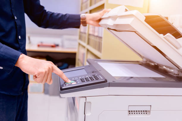 istock Close-up business man Hand press button on panel of printer, printer scanner laser office copy machine supplies start concept. 1004836474