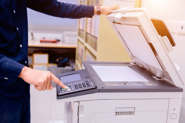 istock Close-up business man Hand press button on panel of printer, printer scanner laser office copy machine supplies start concept. 1004836490