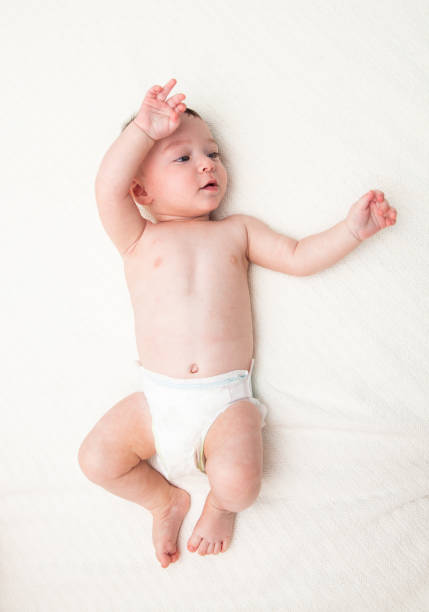 istock Baby boy in diapers full length looking away on white 1004836520