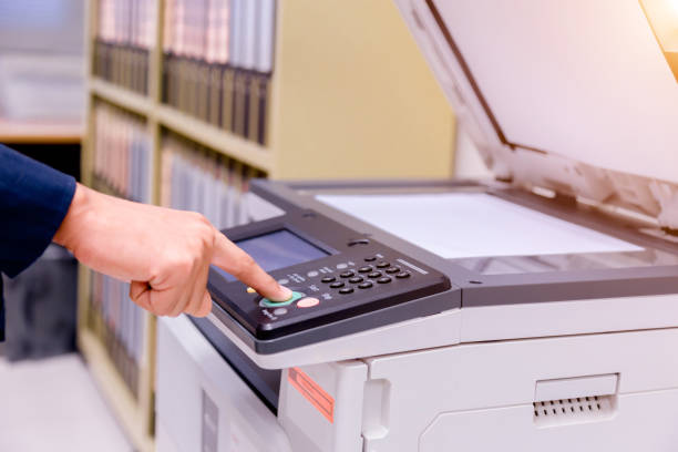 istock Close-up business man Hand press button on panel of printer, printer scanner laser office copy machine supplies start concept. 1004837374